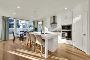 Kitchen featuring white cabinetry, a kitchen island with sink, stainless steel appliances, a kitchen bar, and recessed lighting