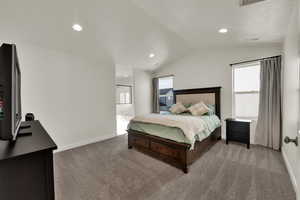 Carpeted bedroom with vaulted ceiling, recessed lighting, and ensuite bathroom