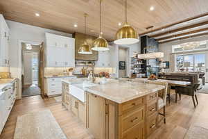 Kitchen with a kitchen breakfast bar, decorative light fixtures, white cabinets, light wood-type flooring, and wooden ceiling