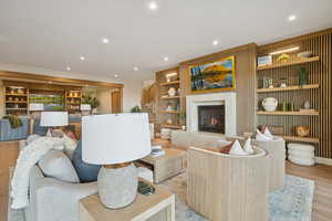 Living area with wood finished floors, a high end fireplace, recessed lighting, and built in shelves