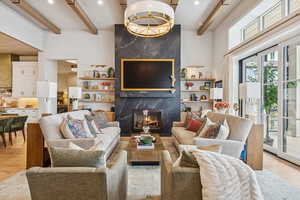 Living room featuring light wood-style floors, beamed ceiling, and a fireplace
