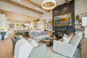Living area with beam ceiling, light wood-style flooring, a chandelier, a premium fireplace, and recessed lighting