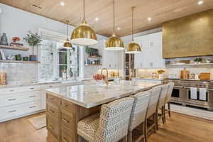 Kitchen with open shelves, white cabinetry, light stone counters, range with two ovens, and wood ceiling