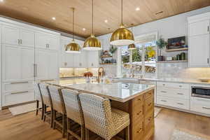 Kitchen with white cabinetry, open shelves, light stone countertops, recessed lighting, and decorative light fixtures