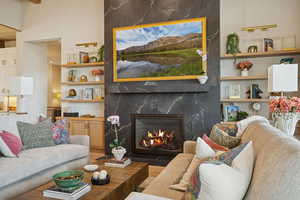 Living room with wood finished floors, a premium fireplace, and built in shelves