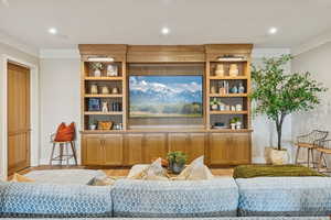 Living room with wood finished floors, recessed lighting, and crown molding