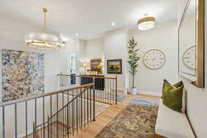 Hallway featuring an upstairs landing, light wood-type flooring, and recessed lighting