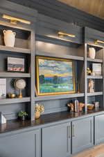 Bar area with open shelves, gray cabinets, dark stone counters, and light wood-type flooring