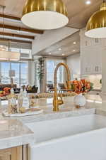 Kitchen view of pendant lighting, white cabinets, light stone countertops, and recessed lighting