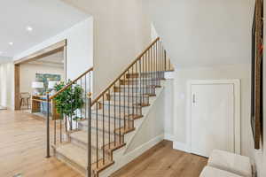 Stairway with wood finished floors and recessed lighting