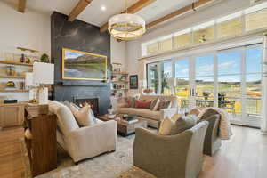 Living room featuring wood finished floors, beam ceiling, a premium fireplace, and a high ceiling