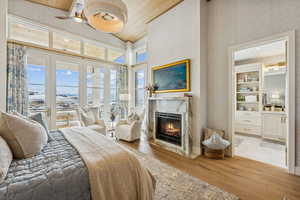 Bedroom featuring light wood finished floors, access to outside, a fireplace, ceiling fan, and wood ceiling