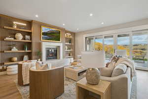Sitting room featuring light wood-type flooring, a glass covered fireplace, recessed lighting, and built in features