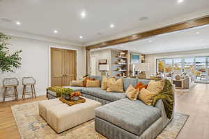 Living room with light wood finished floors, recessed lighting, and ornamental molding
