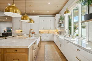 Kitchen featuring white cabinetry, recessed lighting, light stone counters, decorative light fixtures, and wood ceiling