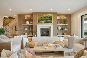 Living area with built in features, a premium fireplace, recessed lighting, and stairway
