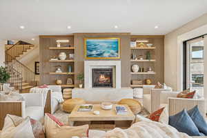 Living room featuring built in features, a fireplace, stairway, and recessed lighting
