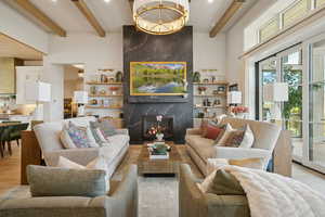Living area featuring beam ceiling, a chandelier, a high end fireplace, and wood finished floors
