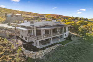 Rear view of property with a chimney, a patio, stone siding, a metal roof, and a standing seam roof