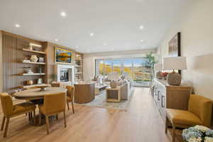 Living area with a glass covered fireplace, light wood-style floors, recessed lighting, and built in features