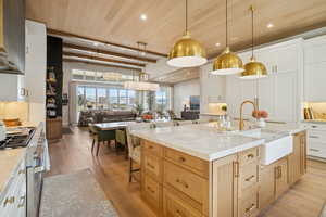 Kitchen with backsplash, a kitchen breakfast bar, white cabinets, recessed lighting, and a wood ceiling with exposed beams