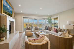 Living area with wood finished floors, a high end fireplace, and recessed lighting