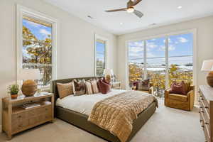 Bedroom featuring light colored carpet, multiple windows, access to exterior, and ceiling fan