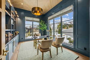 Dining space featuring a decorative wall, light wood-style floors, an office area, and wood ceiling