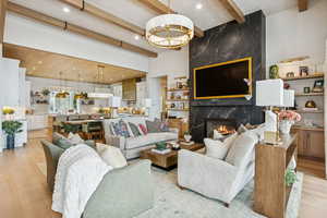 Living room with light wood-style flooring, beam ceiling, recessed lighting, and a fireplace