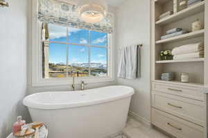 Full bath featuring a freestanding bath, built in shelves, and a mountain view