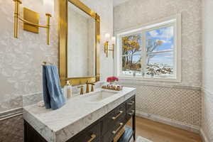 Bathroom featuring wallpapered walls, light wood-style flooring, and vanity