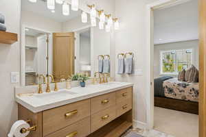 Ensuite bathroom with double vanity, light colored carpet, and recessed lighting