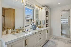 Full bathroom with double vanity, wallpapered walls, a stall shower, and light tile patterned flooring