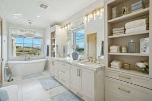 Full bathroom featuring double vanity, a soaking tub, plenty of natural light, and built in shelves