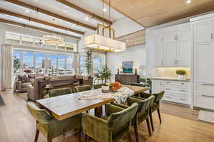 Dining room with recessed lighting, light wood-style flooring, beamed ceiling, and a chandelier