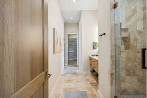 Bathroom with a walk in closet, vanity, a shower stall, and recessed lighting