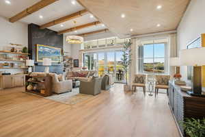 Living area with beamed ceiling, light wood-style floors, a towering ceiling, a chandelier, and recessed lighting