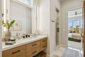Ensuite bathroom featuring vanity, a stall shower, and ceiling fan
