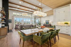Dining area featuring light wood-type flooring, beamed ceiling, recessed lighting, a high ceiling, and a chandelier