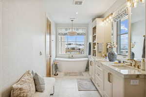 Full bathroom featuring a freestanding bath, double vanity, and light tile patterned floors