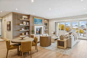Living area with recessed lighting, a glass covered fireplace, light wood finished floors, and built in shelves