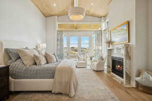 Bedroom featuring wood finished floors, a high end fireplace, access to outside, wood ceiling, and high vaulted ceiling
