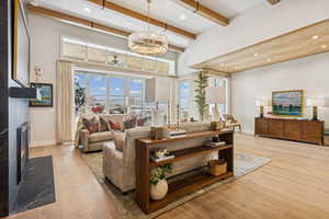 Living room with a high end fireplace, light wood-type flooring, healthy amount of natural light, recessed lighting, and beamed ceiling