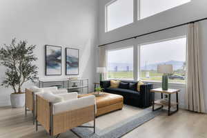 Living area with light wood-type flooring, a high ceiling, and a mountain view