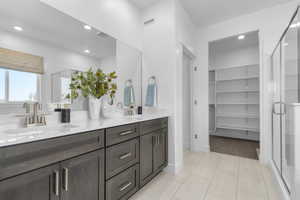 Bathroom with a stall shower, double vanity, a spacious closet, recessed lighting, and light tile patterned flooring