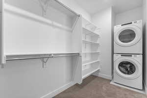 Laundry room with light colored carpet and stacked washer and clothes dryer