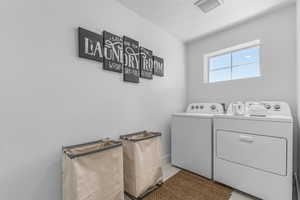 Laundry area featuring washing machine and clothes dryer, a textured ceiling, and light tile patterned floors