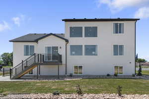 Back of house with a yard, a wooden deck, stairway, and stucco siding