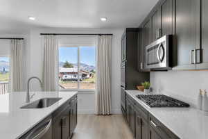 Kitchen featuring light stone counters, stainless steel appliances, light wood-style flooring, a mountain view, and a textured ceiling