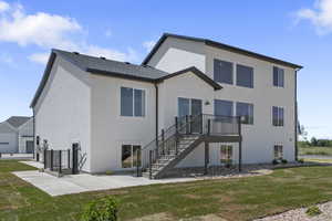 Rear view of property with a lawn, stairway, and stucco siding